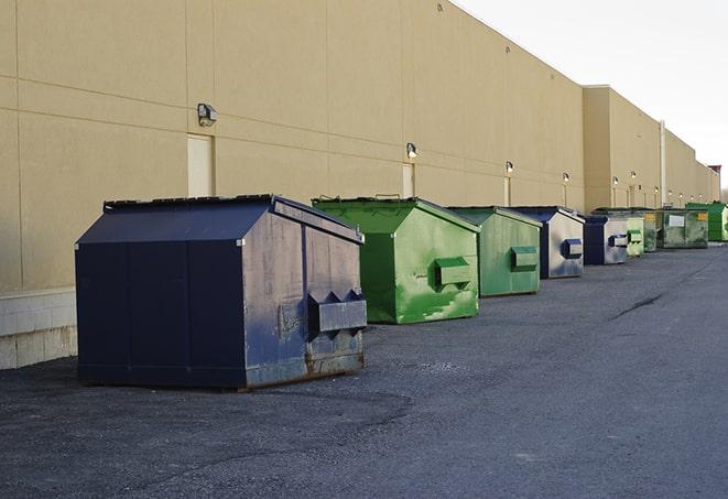 a series of colorful, utilitarian dumpsters deployed in a construction site in Ashville